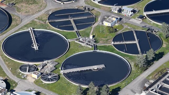 Aerial view of circular water treatment pools creating a geometric pattern, contrasted against the surrounding green landscape, Sausheim, Grand Est, France.