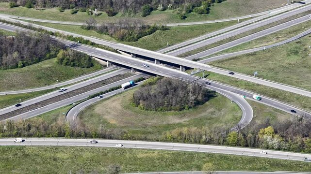 Aerial view of a complex highway interchange cutting through lush green fields, creating a stark contrast between nature and infrastructure, Sausheim, Grand Est, France.