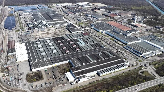 Aerial view of industrial complex featuring various buildings, solar panels, and roads, creating a contrast between urban development and nature, Sausheim, Grand Est, France.