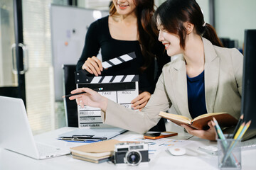 Creative team planning video production in modern office, using clapperboard, laptop and notebook. Business, marketing, content creation © Nuttapong punna