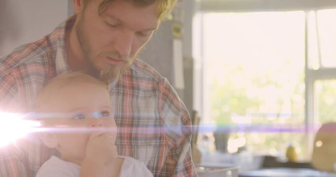 Father holding infant at kitchen counter, baby reaching crumb, father soothing, baby smiling