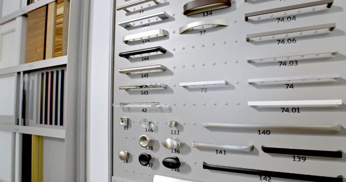 Display board with various metal cabinet handles and knobs in a furniture showroom