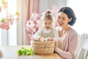 Mother and Daughter Placing Decorated Easter Eggs in Basket