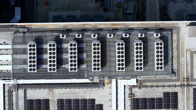 Aerial top down view of industrial rooftop HVAC ventilation and air conditioning units with spinning fans