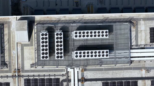 Aerial top down view of industrial rooftop HVAC ventilation and air conditioning units with spinning fans