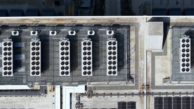 Aerial top down view of industrial rooftop HVAC ventilation and air conditioning units with spinning fans