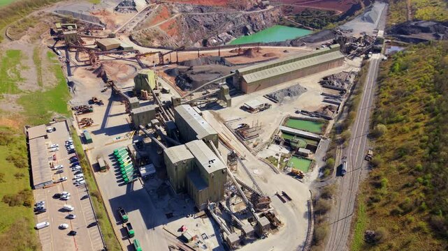 Aerial drone view of a massive industrial quarry in Coalville, UK, featuring conveyor belts, grading buildings, and heavy plant machinery.