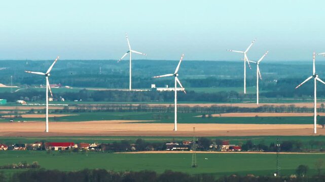 Zoom view of spinning wind turbines in Lower Silesia from distance, sunny and windy weather