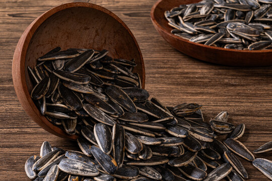 Spilled wooden bowl of dried sunflower seeds on rustic table surface