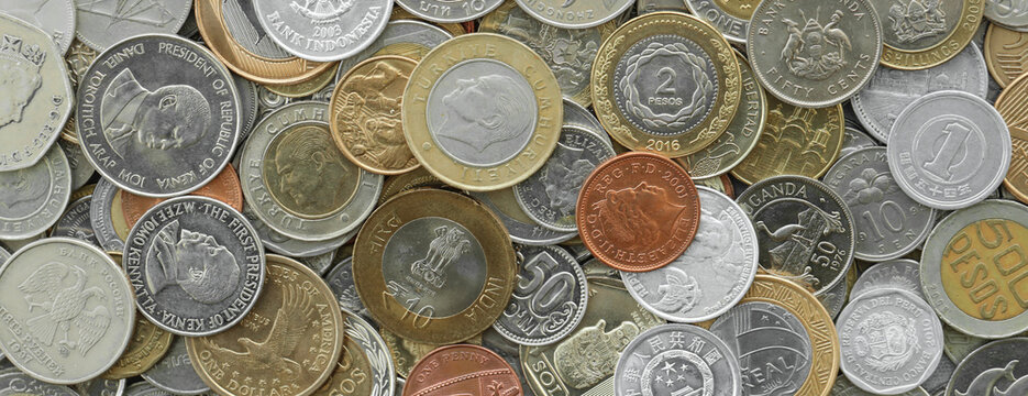 Pile of global currencies, various coin types visible up close. Different nations money together