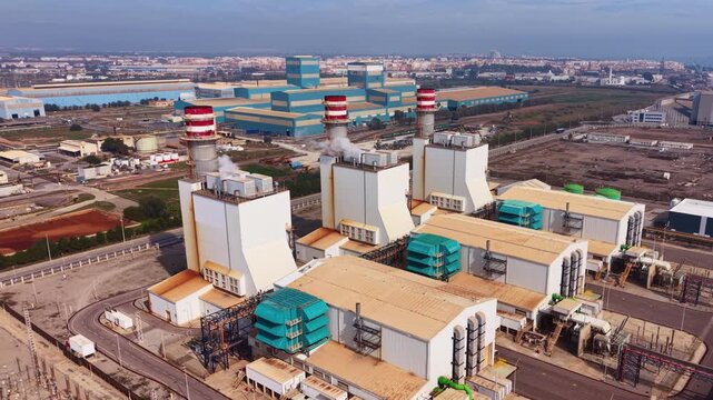 Combined cycle gas power plant with turbines, heat recovery steam generators, exhaust stacks and high-voltage switchyard delivering electricity to transmission grid