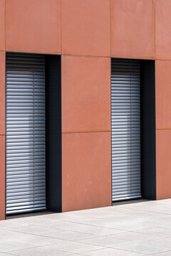 Minimal urban architecture with concrete geometry pattern on orange facade featuring shutters and doors for abstract building background and design detail