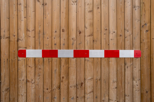 Minimal safety barrier with red white stripe across texture wood wall forming graphic pattern for urban construction concept background