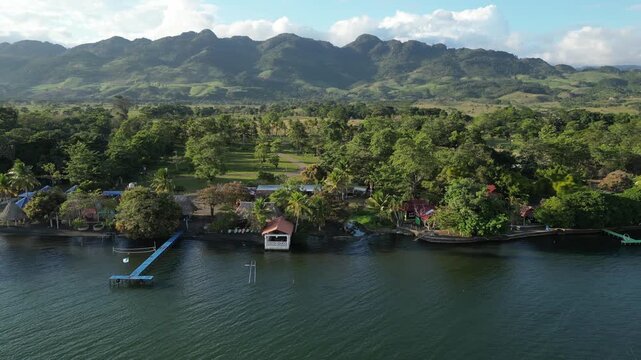 Lake Izabal shoreline in Guatemala with lakeside fincas, revealing farmland, fields, and trees in background under soft low sun light.
