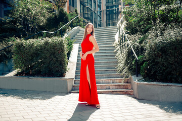 Woman in a red dress posing on urban steps, fashion model portrait conveying elegance and confidence in a summer city setting © deagreez