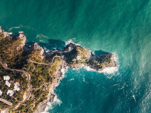 Aerial view of the rugged coastline meeting the turquoise sea in a dramatic clash of textures and tones, Sorrento, Campania, Italy.
