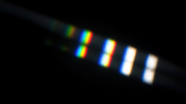 Diffracted light creates rainbow spectrum patterns across a dark background