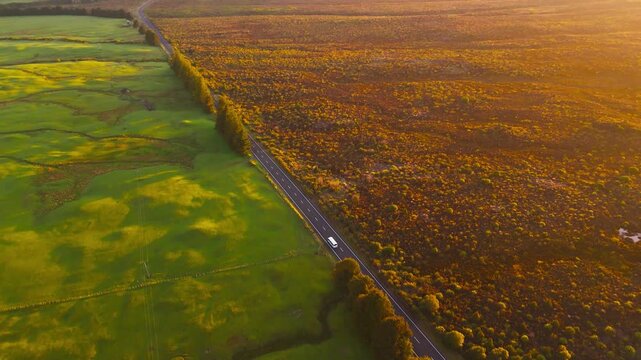 Landscape divides farmland and native scrub at Tongariro National Park, golden hour aerial pan up.