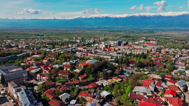 Aerial view of Telavi with the Caucasus mountain range rising behind the city, highlighting the contrast between urban texture and rugged landscape.