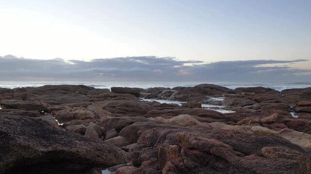 The tranquil sea meets a rugged coast with rocky outcrops and tide pools reflecting the soft morning sky at Ramsgate, South Coast.