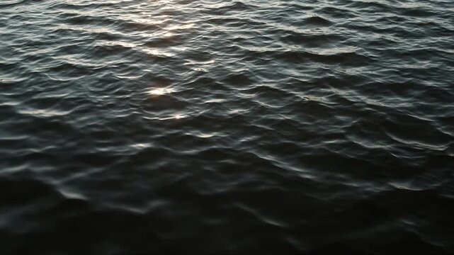Dark mysterious video of slow breeze on water. Still lake water and small waves.
