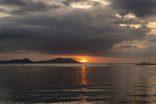 Solitary fishing boat sailing at sunset on calm water