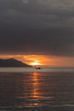 Solitary fishing boat sailing at sunset on calm water