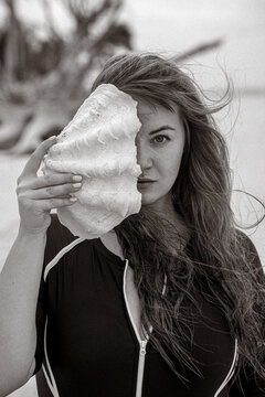 Giant Seashell by Woman&rsquo;s Face on Beach, Black and White Artistic Portrait
