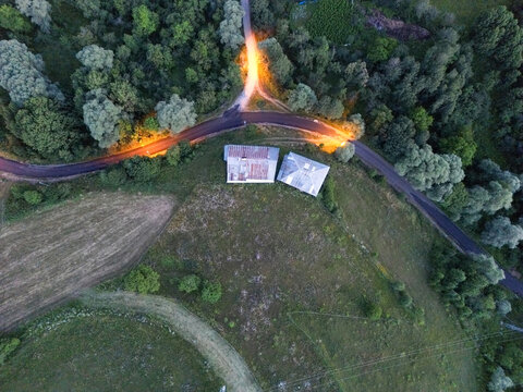 Aerial view of a farm with metallic roofed buildings under warm streetlights amidst a vibrant green landscape, Posof, Ardahan, Turkey.