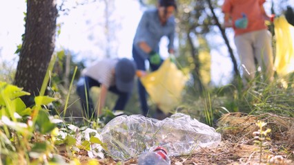 Volunteers picking up plastic waste and trash from a forest floor, focusing on environmental protection, conservation, and community cleanup efforts reducing pollution © NJF
