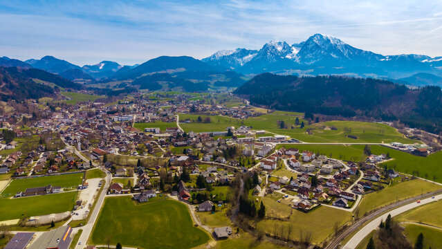 Aerial view of the charming Windischgarsten valley nestled amidst rolling green hills, with the majestic snow-capped Alps piercing the horizon, Windischgarsten, Upper Austria, Austria.