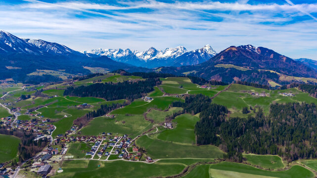 Aerial view of the vibrant green valley floor meets the jagged, snow-capped peaks, creating a stunning alpine contrast, Windischgarsten, Upper Austria, Austria.