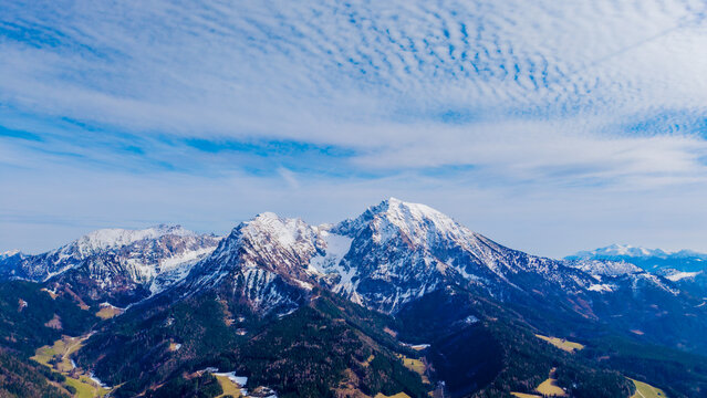Aerial view of snow-dusted peaks pierce the sky, their rugged slopes contrasting with the lush green valleys below, Windischgarsten, Upper Austria, Austria.