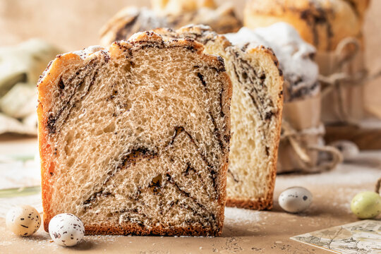 Easter cakes cruffins (Kulich) with poppy seed filling cutted sprinkled with powdered sugar on beige textured background. Easter bread, easter eggs
