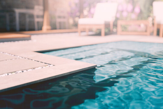 Luxury pool edge closeup in modern beach summer house backyard. Summer holiday hotel rental. Closeup of tropical poolside patio stage with sunlight. Swimming pool design architecture.