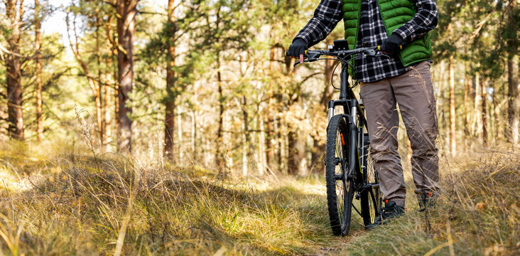 Man with bicycle on forest trail. Outdoor activity. banner with copy space