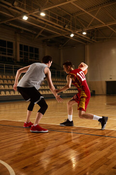 Two basketball players competing on indoor court during game action moment. Concept of sports rivalry, athletic performance, training session, active lifestyle, and professional game practice.