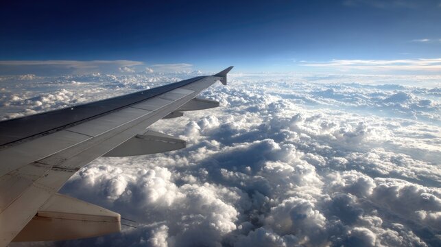 Aerial View from Airplane Wing Over Lush Clouds and Blue Sky During Daylight Flight Journey in the Open Air