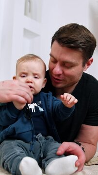 Little child holding black beads bracelet in hands. Father takes away the toy from kid giving him a pacifier.