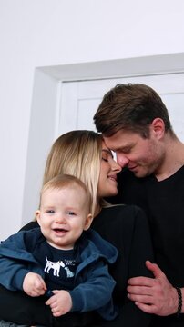 Happy Caucasian couple with their smiling baby in hands. Beautiful family portrait of three.