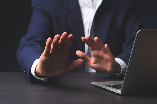 Business person gesturing stop while working on laptop
