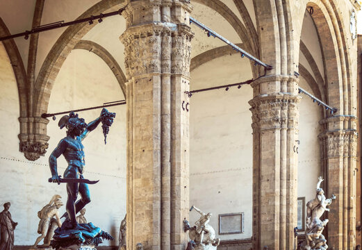 Perseus and Medusa by Cellini beneath the Loggia dei Lanzi in Florence, framed by historic arches and Renaissance grandeur