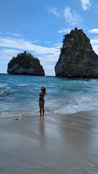 Blonde woman in bikini at Diamond Beach Bali Indonesia, tropical paradise with turquoise ocean and iconic cliffs, smiling female posing on sandy shore, travel wellness moment in exotic island seascape