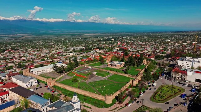 Drone footage of Telavi, Georgia, showing the cityscape and regional landscape with the Caucasus mountains creating a dramatic natural setting.