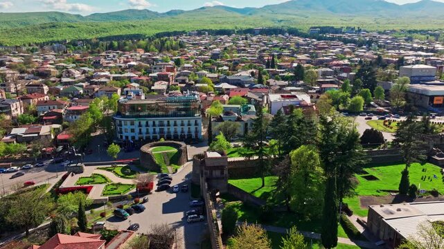 Drone shot above Telavi, Georgia, featuring the city surrounded by scenic terrain and framed by the expansive Caucasus mountain backdrop.