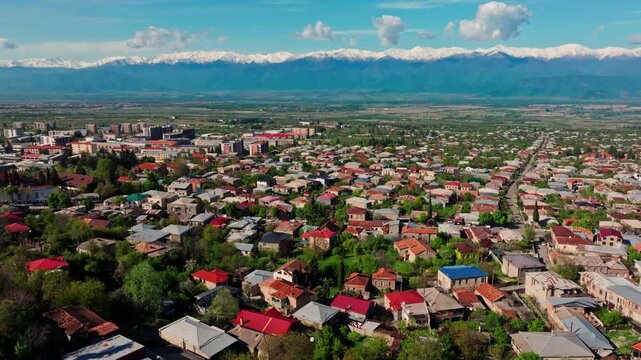 Aerial perspective over Telavi, capturing the Georgian city, surrounding countryside, and the striking Caucasus range stretching across the horizon.