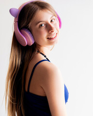 Naklejka premium Studio Portrait of a Blonde Pre-teen Girl in Blue Clothing Wearing Pink Headphones