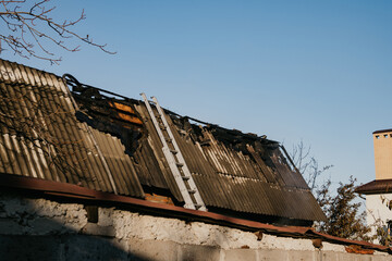 House damaged by fire with ladder leaning against the roof © Maria