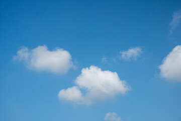 Obraz premium Small white fluffy clouds scattered across a bright blue sky