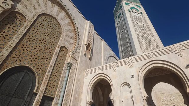 pan view of Hassan II Mosque against sky , Hassan II Mosque minaret looking up through arches - Hassan II Mosque minaret upward view through ornate arches Casablanca, Morocco